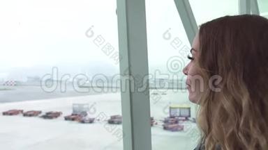 旅行妇女在候机室的飞机上寻找机场候机窗口。 女游客寻找窗口